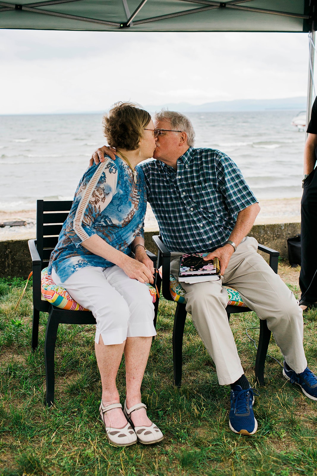 Older couple kissing under a beach umbrella