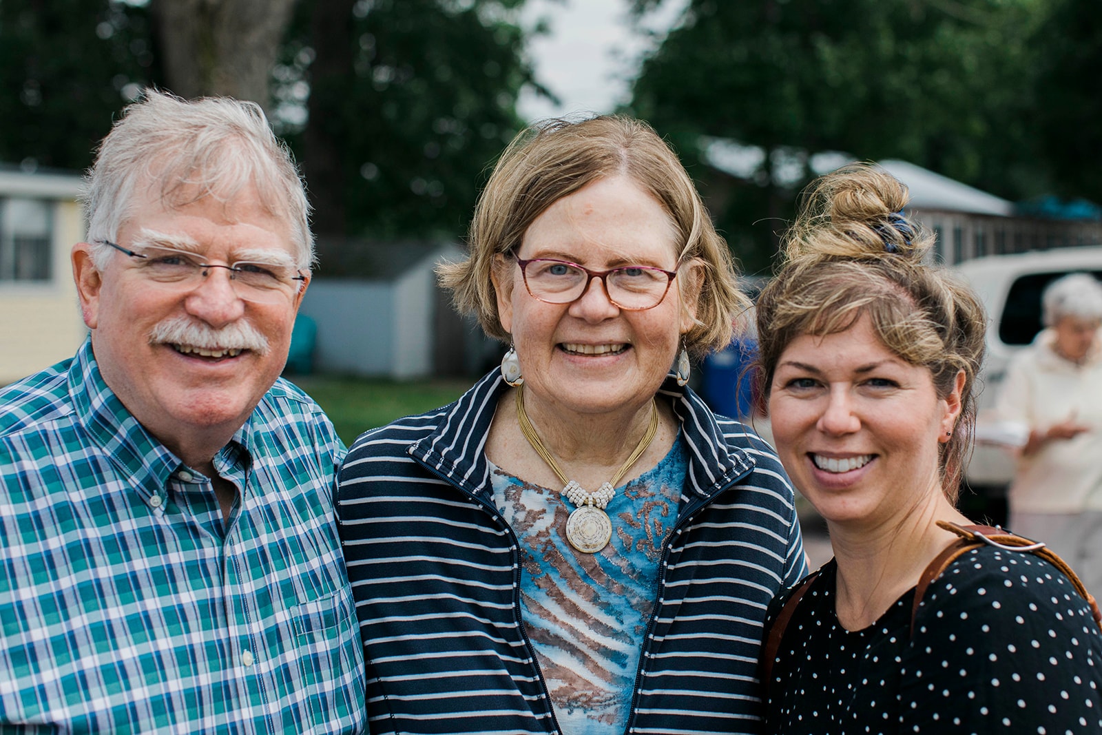 Three people smiling together outdoors
